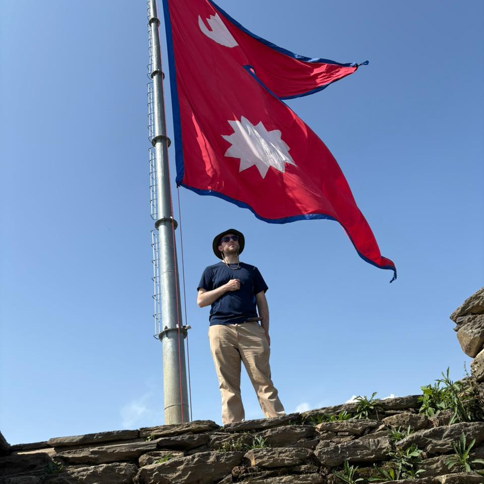 Volunteer beneath the Nepali flag